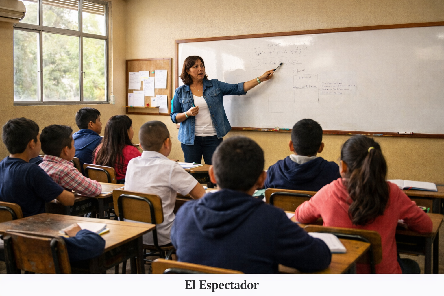 Docente explicando clase a estudiantes en un aula de colegio público colombiano